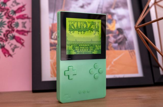 A special edition Analogue Pocket in green is pictured on a shelf with a game onscreen.