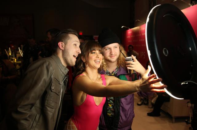 LAS VEGAS, NEVADA - JANUARY 22: Adult film actress Riley Reid (C) takes a selfie with Harrison Hays (L) and Chasen Hallford (R) of Texas in the Reid My Lips booth during the 2020 AVN Adult Expo at the Hard Rock Hotel & Casino on January 22, 2020 in Las Vegas, Nevada. (Photo by Gabe Ginsberg/WireImage)