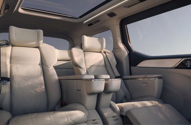 Volvo EM90 interior, showing large windows and sunroof, along with theater-style seats with footrests .