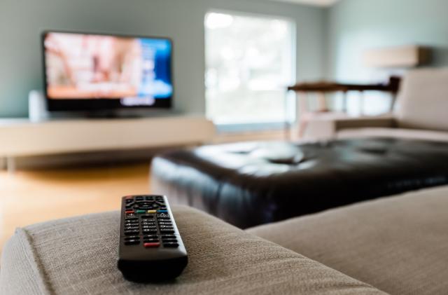 Close-up of a remote control sitting on a couch in an empty modern living room.