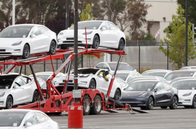 A worker loads a Tesla electric vehicle onto a car carrier trailer at Tesla's primary vehicle factory after CEO Elon Musk announced he was defying local officials' coronavirus disease (COVID-19) restrictions by reopening the plant in Fremont, California, U.S. May 11, 2020. REUTERS/Stephen Lam