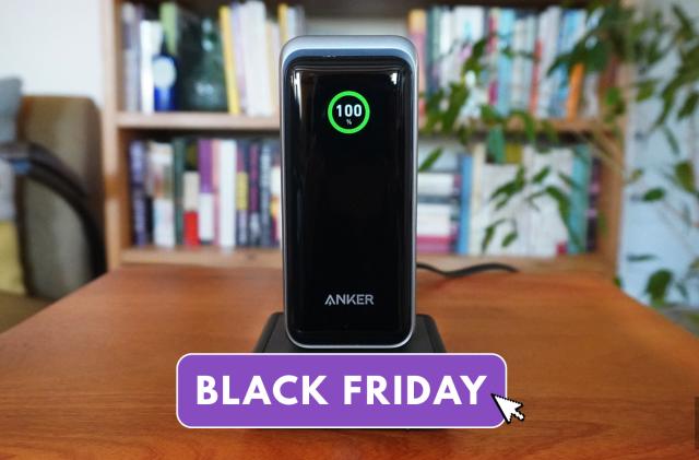The Anker Prime 20k power bank sits on its charging base on a wooden table. Engadget's black friday logo is overlain across the image. 