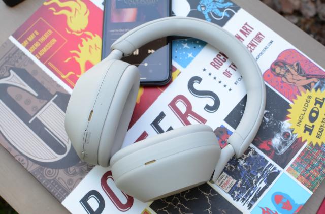 Photo of the Sony WH-1000XM5 headphones in silver sitting on a pile of colorful books.
