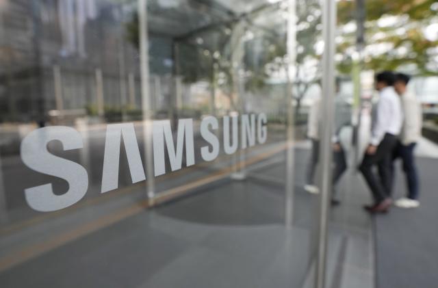 Employees walk past the logo of the Samsung Electronics Co. at its office in Seoul, South Korea,Tuesday, Oct. 31, 2023. Samsung Electronics on Tuesday reported its highest quarterly profit for the year and saw narrowed losses from its computer chip business amid a slow recovery in global demand.(AP Photo/Ahn Young-joon)