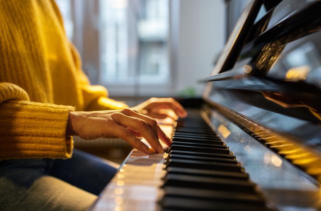 Close-up of female hands playing piano. Woman learning to play piano at home.