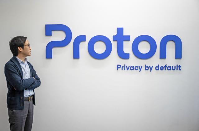 Proton CEO and founder Andy Yen poses next to the Proton logo at the headquarters of the encrypted email and VPN services company in Geneva on February 21, 2023. - Internet privacy company Proton can spot attacks on democracy in a country before it hits the headlines, simply by watching demand for its services explode, its chief told AFP. 