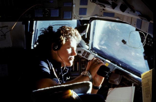 41G-11-027 (14 Oct. 1984) --- Kathryn D. Sullivan, 41-G mission specialist, uses a pair of binoculars to do some magnified viewing through the forward cabin windows of the Earth-orbiting space shuttle Challenger. The 35mm frame was part of the first photographic release from the eight-day 41-G mission on Oct. 14, 1984. Photo credit: NASA